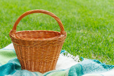 Picnic basket on a green lawn under sunny skies, ready for an outdoor meal. With copy space