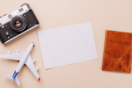 Travel-themed flat lay with blank photo card, camera, toy airplane, and passport, arranged creatively on table with copy space for your ideasの写真素材