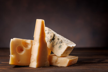 Assorted cheeses in different shapes and textures displayed together on a rustic surface