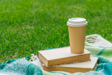 Books and coffee on a sunny lawn, perfect for a relaxing picnic momentの写真素材