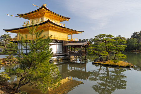 The Golden Pavilion (Kinkaku-ji) in Kyoto, Japan, reflects gracefully in a tranquil pond, surrounded by lush greenery a serene symbol of Zen beauty and Japanese heritageの写真素材