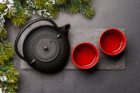 Christmas tea setting with teapot, cups, and fir tree branches creating a cozy festive moodの写真素材