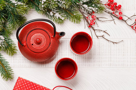Christmas tea setting with teapot, cups, and fir tree branches creating a cozy festive moodの写真素材