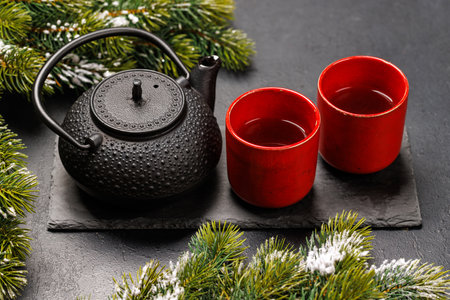 Christmas tea setting with teapot, cups, and fir tree branches creating a cozy festive moodの写真素材