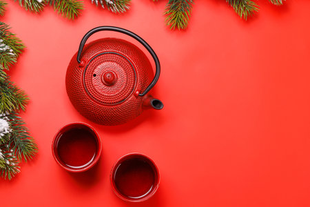 Christmas tea setting with teapot, cups, and fir tree branches creating a cozy festive moodの写真素材