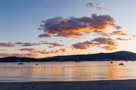 Sunset over the Bay of Kotor in Montenegro with calm sea and mountain silhouettesの写真素材