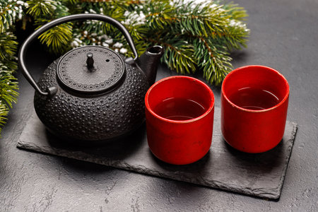 Christmas tea setting with teapot, cups, and fir tree branches creating a cozy festive moodの写真素材