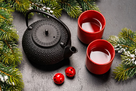 Christmas tea setting with teapot, cups, and fir tree branches creating a cozy festive moodの写真素材