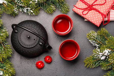 Christmas tea setting with teapot, cups, and fir tree branches creating a cozy festive moodの写真素材