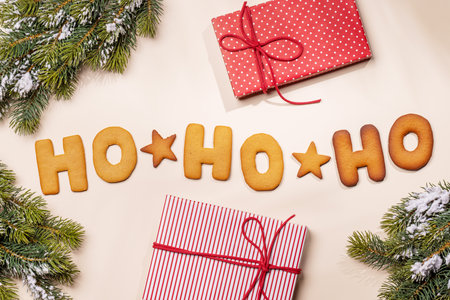 Ginger cookies shaped as Ho Ho Ho with fir branches on beige background, Christmas card styleの写真素材