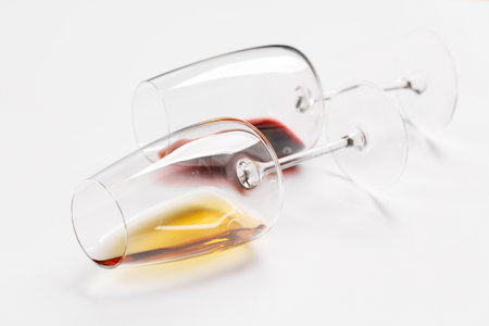 Wine glasses with red and white wine lying on white background, minimal elegant styleの写真素材