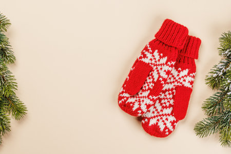 Christmas card with fir branches and mittens on beige surface, festive holiday with copy spaceの写真素材