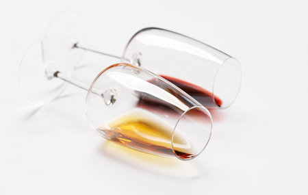 Wine glasses with red and white wine lying on white background, minimal elegant styleの写真素材