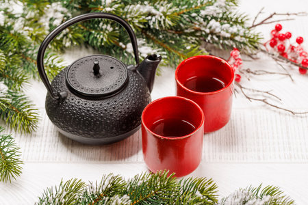 Christmas tea setting with teapot, cups, and fir tree branches creating a cozy festive moodの写真素材