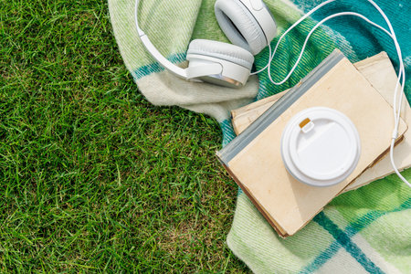 Books, coffee, and headphones on a sunny lawn, perfect for a relaxing picnic momentの写真素材