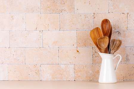 Kitchen utensils on table near beige stone wall, rustic home interior with copy spaceの写真素材