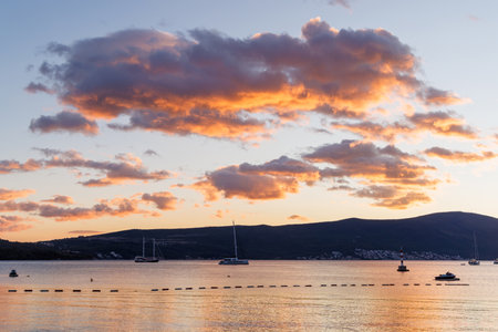 Sunset over the Bay of Kotor in Montenegro with calm sea and mountain silhouettesの写真素材
