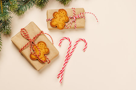 Christmas card with fir branches, gifts and cookies on beige surface, festive holiday