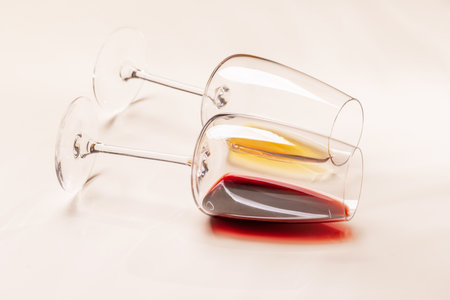 Wine glasses with red and white wine lying on beige background, minimal elegant styleの写真素材