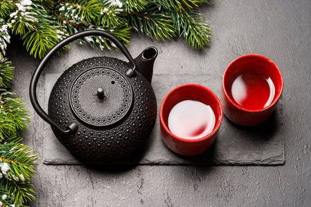 Christmas tea setting with teapot, cups, and fir tree branches creating a cozy festive moodの写真素材