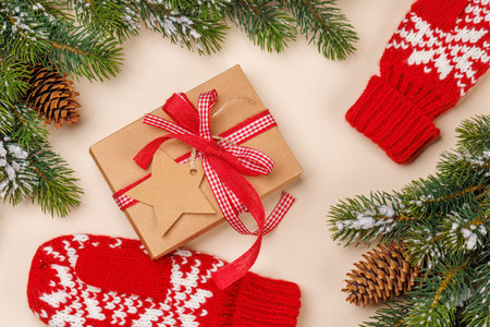 Gift box on snowy fir branches and beige background with copy space, festive Christmas compositionの写真素材