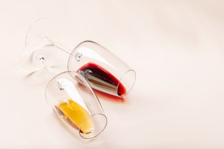 Wine glasses with red and white wine lying on beige background, minimal elegant styleの写真素材