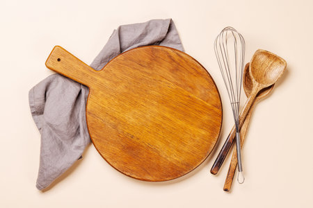Empty cutting board and kitchen utensils on beige table, top view with copy space, minimal cooking sceneの写真素材