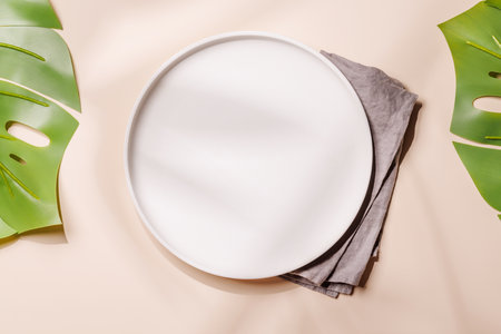 Empty plate on white background with leaves and shadows, food mockup with natural light. Flat layの写真素材