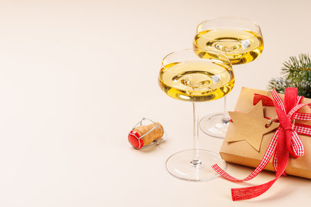 Two champagne glasses and snowy fir branches on beige background, with copy spaceの写真素材