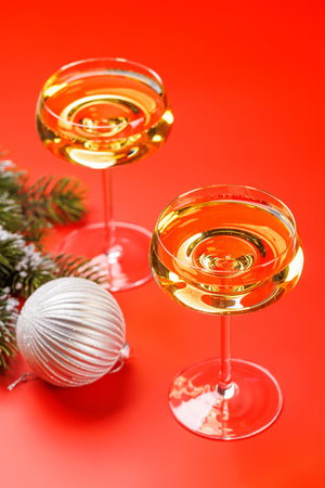 Two champagne glasses and snowy fir branches on red background, with copy spaceの写真素材