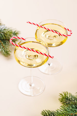 Two champagne glasses and snowy fir branches on beige background, with copy spaceの写真素材