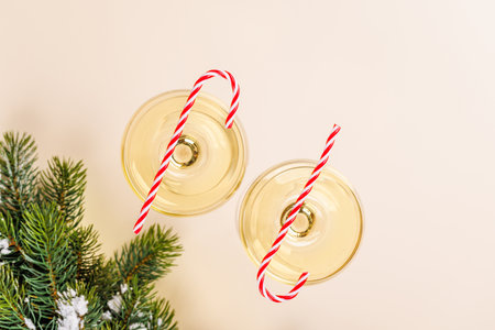 Two champagne glasses and snowy fir branches on beige background, Christmas card with copy spaceの写真素材