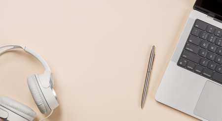 Laptop and stationery on beige workspace, top view with copy space, minimal office background