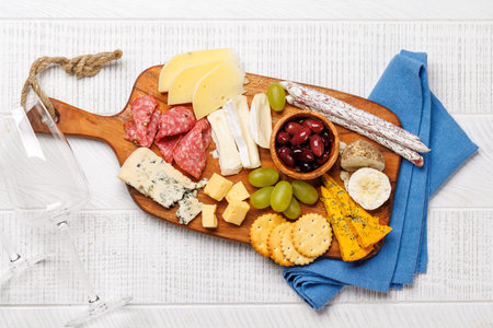 Antipasto served on a wooden board with assorted cheeses, cured meats, olives and grapes
