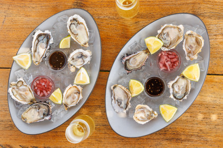 Fresh oysters served on ice with lemon, sauces and champagne, luxury seafood dining concept
