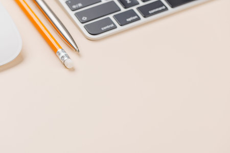 Keyboard, pen and glasses on beige desk, clean workspace background with copy space