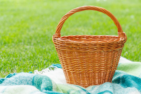 Picnic basket on a green lawn under sunny skies, ready for an outdoor meal. With copy space