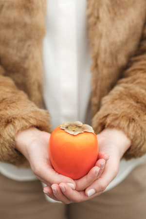Woman holding a kaki fruitの写真素材