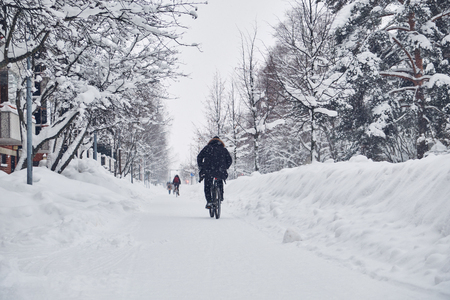 City streets after winter snowstorm blizzard. The cyclist rides in winter on the snowy streetの写真素材