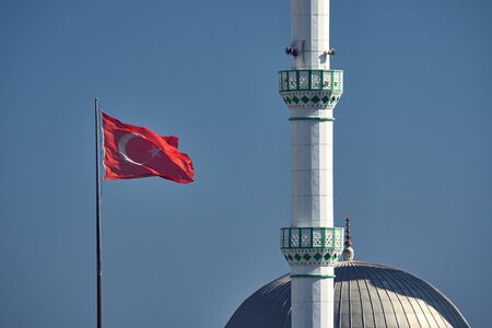 Turkish flag and minaret of a mosque in the Turkish city of Side on a background of blue sky
