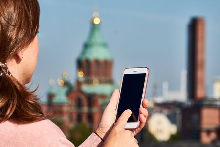 Woman taking a picture on her smartphone of Uspenski Cathedral background, Helsinki, Finlandの写真素材
