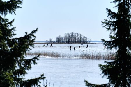 Weekend on the ice-covered lake in Joensuu, Finland. People ride bikes, play hockey, walking on the lake ice.の写真素材