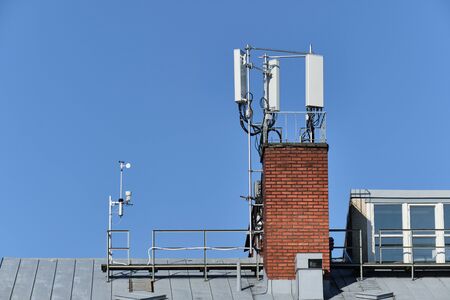 Cellular phone network telecommunication tower and weather station on the building roof.