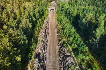Aerial view of the railway track. The railroad between the hills goes into a tunnel.