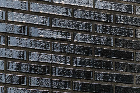 The black glossy brick wall of a modern apartment building. Modern nordic architecture. Pattern of...