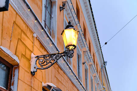 The vintage street lamp on the building during the snowfall. The classic European architecture.の写真素材
