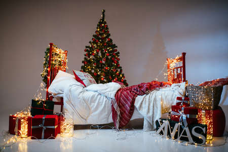 New Year 2021 interior with candles, bulbs and bokeh. Room decorated to christmas celebration. Christmas tree with presentsの写真素材