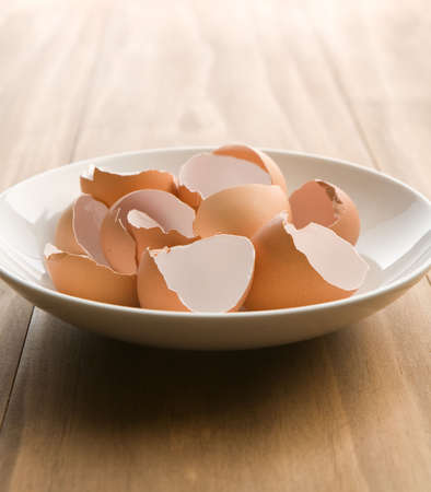 Cracked brown egg shells in a white bowl
