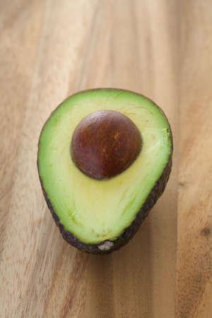 Avocao half with pit still in on wooden tableの写真素材