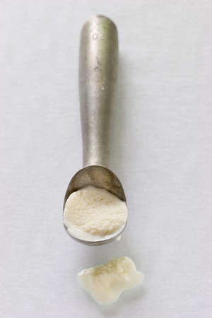 ice cream scoop with melted vannila ice cream in the scoopの写真素材